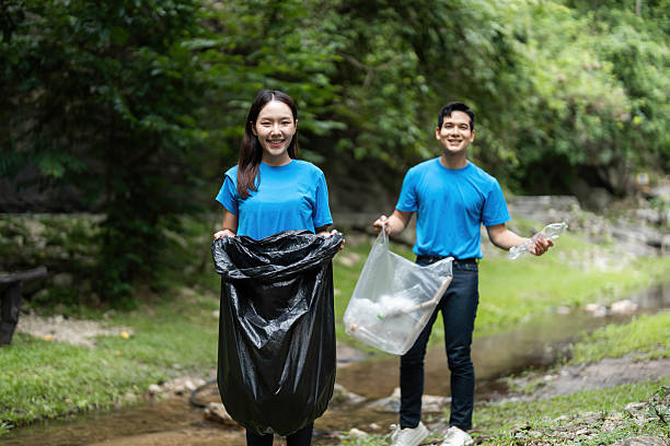 istock Joyful volunteers. Young couple smiling while cleaning nature. 2221105271