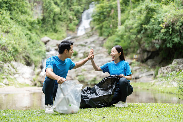 istock Volunteer Teamwork. Two volunteers celebrating a successful clean-up in nature. 2221105346