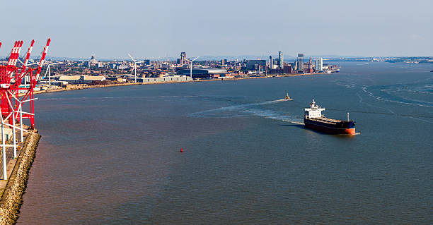 Panoramic Aerial image of a large ship traveling on river Mersey with Liverpool Urban Skyline on the background.