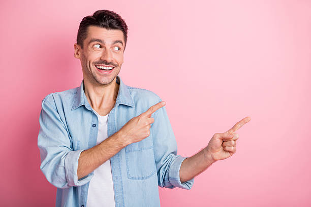 istock Portrait of nice cheerful guy demonstrating copy empty space place ad solution isolated over pink pastel color background 2221109509