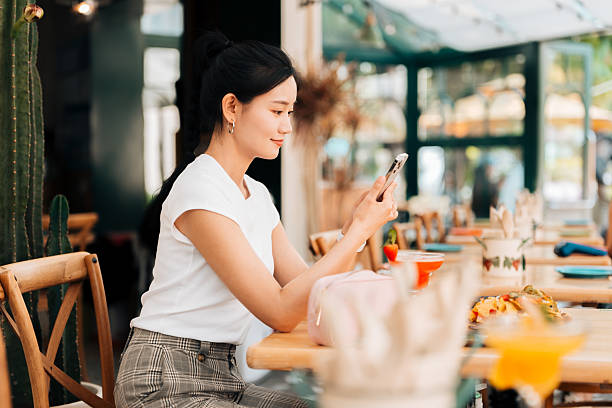 istock Young Asian woman using smartphone while enjoying her lunch in restaurant. Luxury lifestyle. Enjoying life with good food. People, food, lifestyle and technology. 2221114527