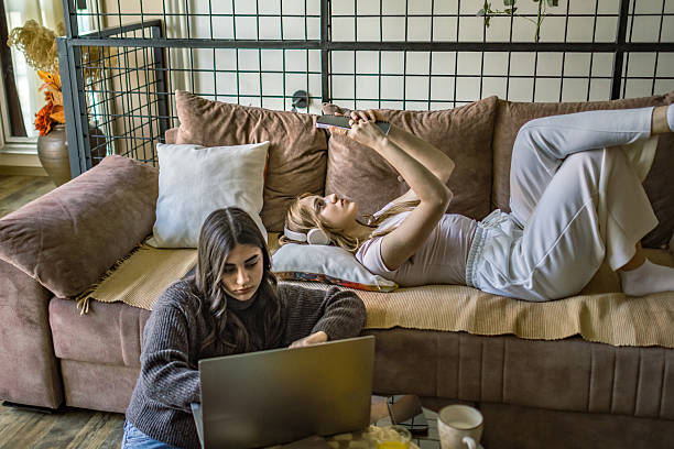 istock Concentrated young women university students learning together for exams at home. Digital nomad roommates working from cozy apartment. 2221121985