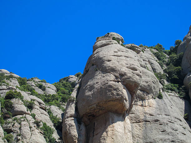 Montserrat mountain rock formations in Spain. Multi-peaked mountain range near Barcelona, in Catalonia. Rocky mountain landscape with unique limestone formations and green vegetation under blue sky
