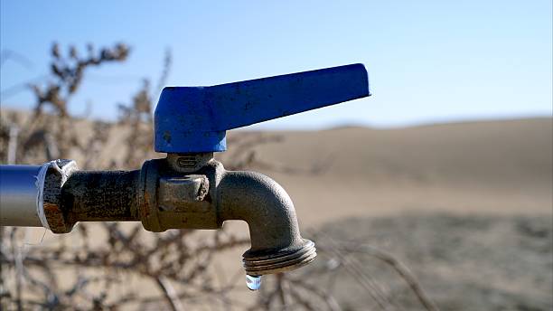 Water dripping from a faucet in a desertic landscape during a drought, highlighting the scarcity of this precious resource due to climate change and desertification