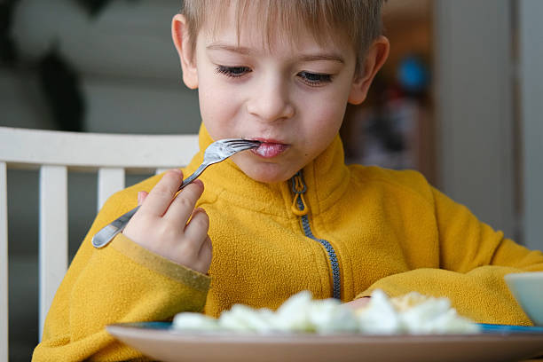 istock 6 years old boy eats pasta with cheese from blue plate. Child is eating spaghetti. Lunch time. Good appetite. Tasty children food. Close-up portrait. Carbs dinner. Fast food. Kid eating with fork. 2221129120