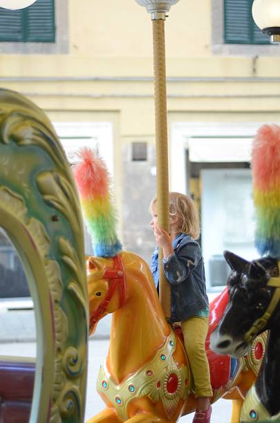 istock Child Riding Carousel Horse at Town Square 2221129656