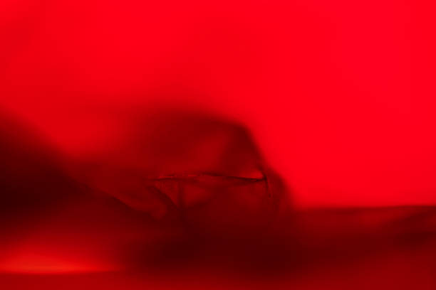Extreme close up of red empty plastic bag background. The plastic surface is wrinkly and tattered making abstract pattern. Selective focus, shallow depth of field.