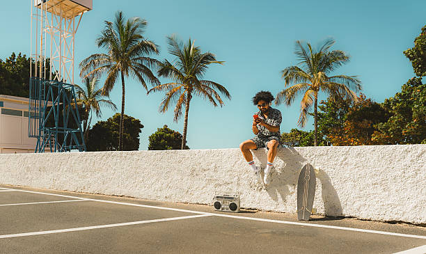 istock African man having fun using smartphone while listening music with beach on background - Vintage and trendy clothes concept - Focus on face 2221131709