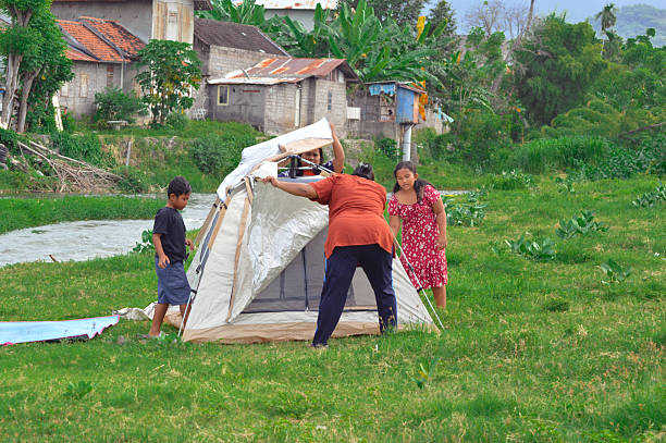 Parents and children actively work together to adjust the tent as they complete their riverside camp preparation