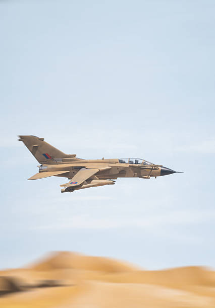 A RAF Tornado GR1 Fighter Jet streaks through the sky, high above the sand dunes of a desert. Scale model photography
