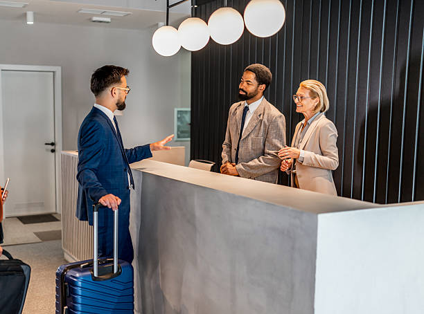 istock Businessman checking in at hotel reception desk with luggage 2221138430