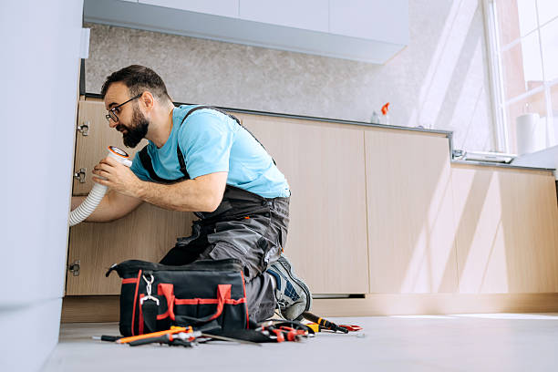 Plumber fixing kitchen sink in apartment Professional plumber working alone under the kitchen sink in a modern apartment. Routine plumbing repair and maintenance in a home setting. Plumbing leak detection stock pictures, royalty-free photos & images