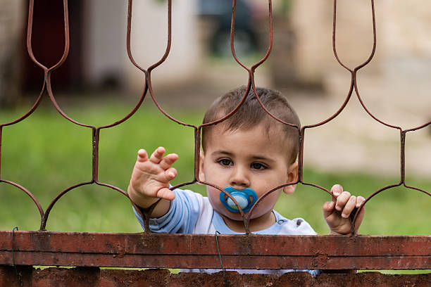 standing baby boy holding the glass with his hands