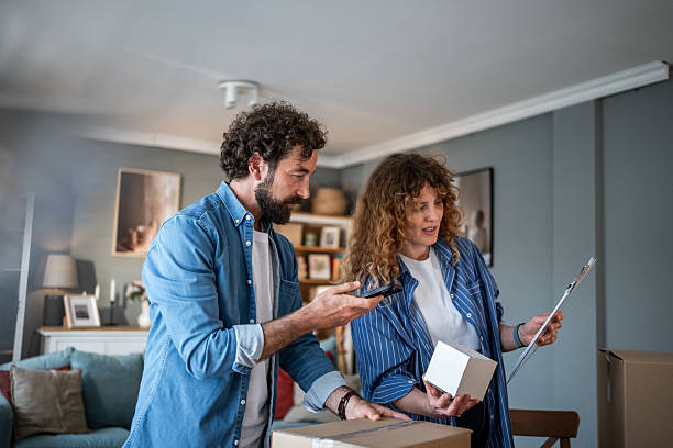 istock Couple taking inventory of belongings using smartphone and clipboard while moving into new home 2221144241