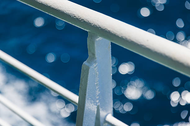 A sharp close-up of a textured white metal railing on a passenger ferry cruising the Adriatic Sea. Captured in bright summer light, the image plays with depth of field—showing crisp details on the railing while softly blurring the vibrant blue ocean and ferry deck behind. This minimalist maritime composition evokes travel, freedom, and the serene experience of ferry transport along Croatia’s scenic coastline. Ideal for editorial, travel, or minimalist design concepts.
