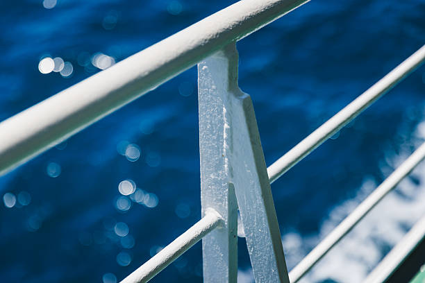 A sharp close-up of a textured white metal railing on a passenger ferry cruising the Adriatic Sea. Captured in bright summer light, the image plays with depth of field—showing crisp details on the railing while softly blurring the vibrant blue ocean and ferry deck behind. This minimalist maritime composition evokes travel, freedom, and the serene experience of ferry transport along Croatia’s scenic coastline. Ideal for editorial, travel, or minimalist design concepts.