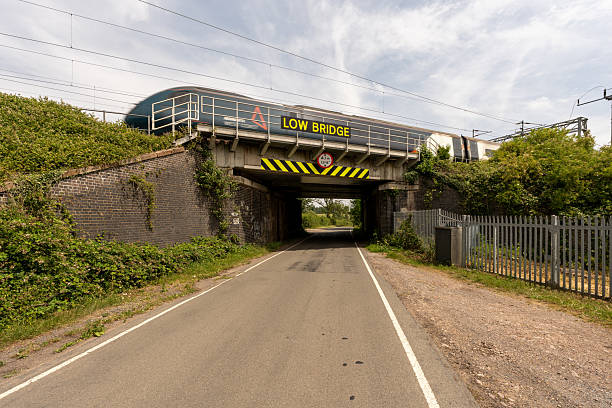 istock Train passing over low bridge on a country road 2221149583