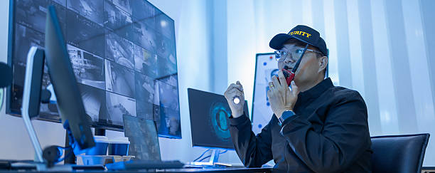 High angle view of security guards working at control room while looking at video wall