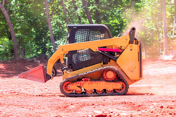 istock Construction equipment operates on dirt site surrounded by trees during works day 2221153203