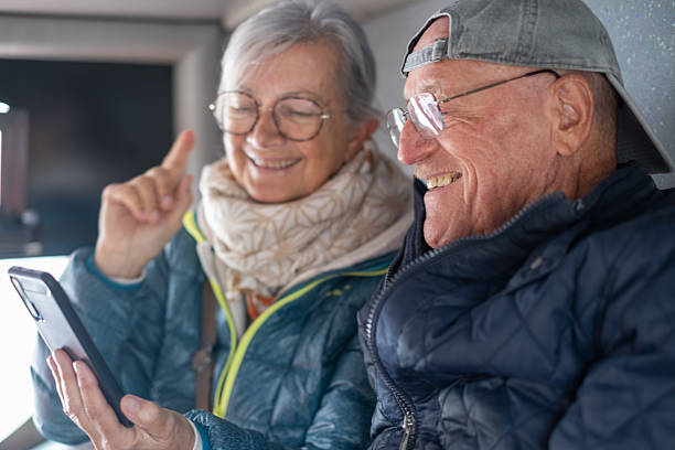 istock Cheerful modern senior couple sitting on a bus while looking together at smartphone sharing tech and social 2221155540