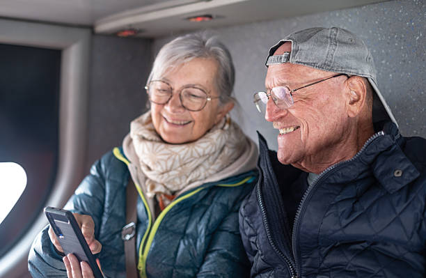 istock Cheerful modern senior couple sitting on a bus while looking together at smartphone sharing tech and social 2221155567
