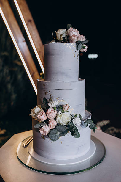 istock Gray Tiered Wedding Cake on Geometric Stand with Floral Backdrop 2221159968