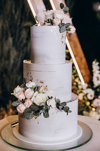istock Gray Tiered Wedding Cake on Geometric Stand with Floral Backdrop 2221160384