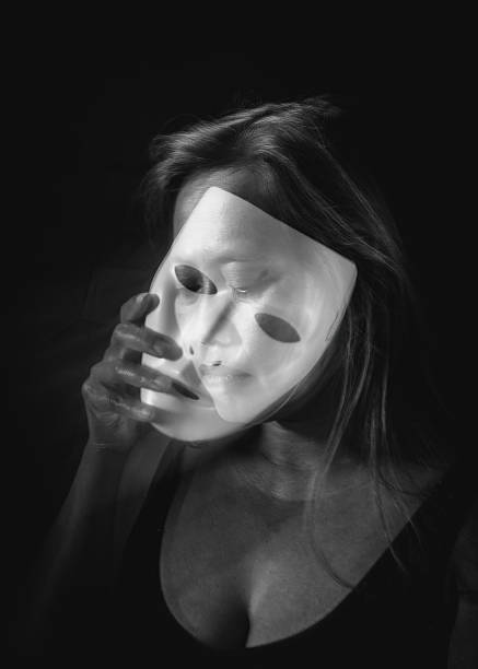 Black and white long exposure portrait of woman holding a translucent mask with motion blur