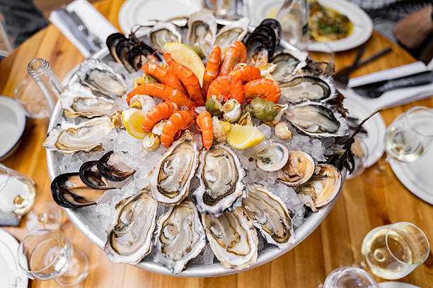 A close-up, overhead view of a vibrant seafood assortment featuring cooked shrimp and crayfish, garnished with fresh green herbs.
