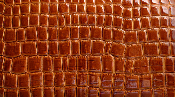 istock Detailed texture of rich brown leather shows a crocodile pattern, highlighting its glossy surface and craftsmanship 2221178561