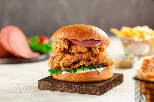 istock Crispy chicken burger with salami light background. 2221180740