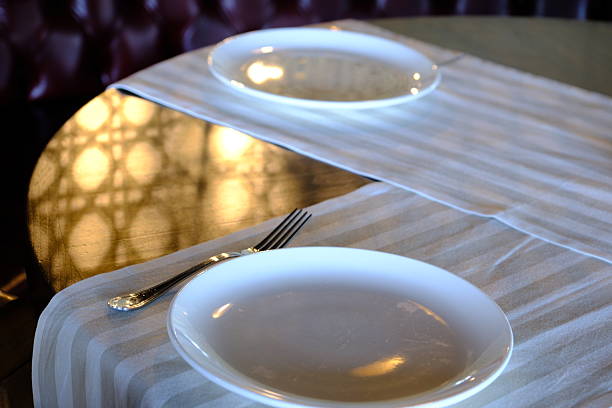 Table arrangement before dinner at a luxury restaurant. Waiters' service preparations. White tablecloths. Design of plates, forks and knives. Celebration dinner, lunch. Restaurant with Bosphorus view. Elegant dining table. Dinner chair.
