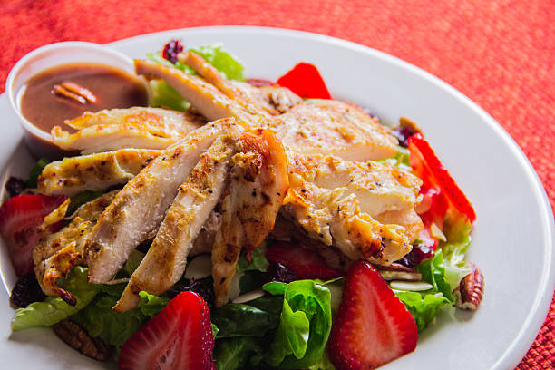 A visually appealing grilled chicken salad featuring fresh greens and strawberries, presenting a perfect blend of healthy ingredients that satisfy both taste and nutritional needs.