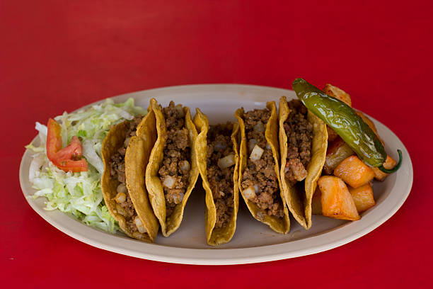 This visually striking image showcases crunchy tacos served on a plate with accompaniments, presenting a delightful arrangement ensconced in the vibrant spirit of Mexican culinary tradition.