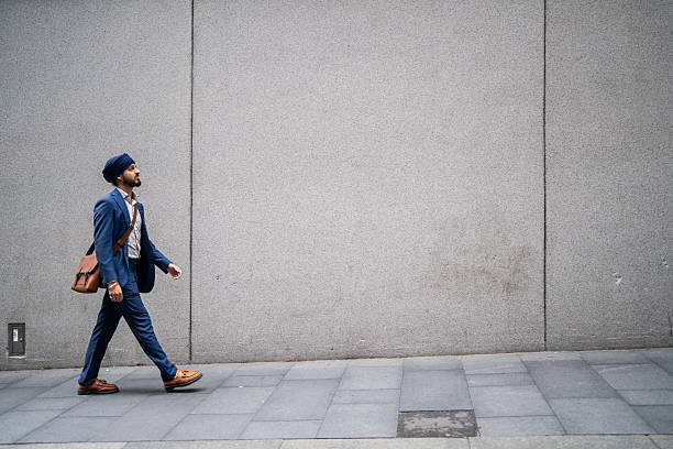 Young Indian businessman walking on sidewalk of downtown Sydney during the workday.