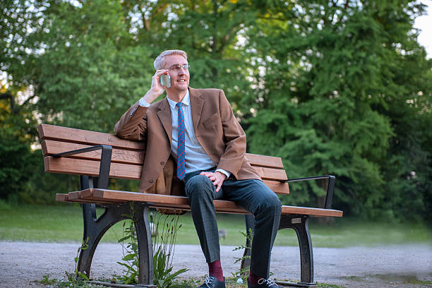 istock Businessman talking on smartphone while relaxing on park bench outdoors. 2221205683