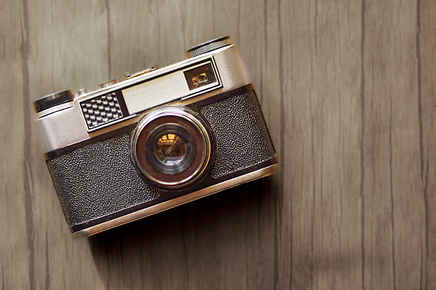 A retro camera lies on a wooden table.