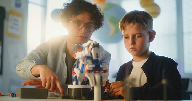 istock Talented Boy Studying Robotic Arm Model with Teacher in Modern Classroom 2221207980