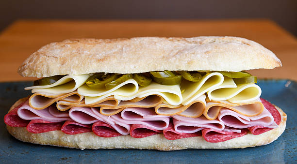 Sandwich with salami, ham, turkey, cheese and pickles on a plate