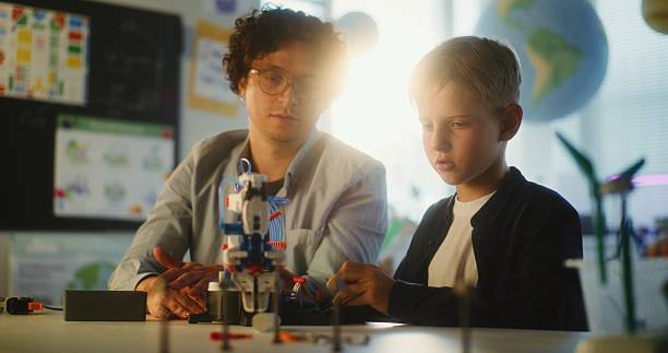 istock Elementary School Student Studying Model of Innovative Robotic Arm. Teacher Educating Smart Young Boy 2221209264