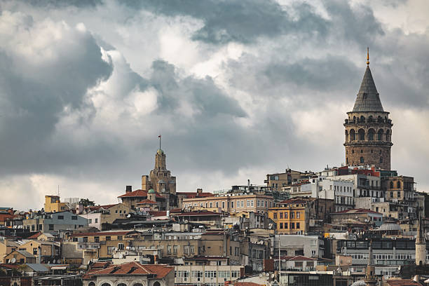 Skyline of Istanbul featuring historic architecture and Galata Tower under dramatic cloudy sky. Istanbul, Turkey. Oct 17, 2022