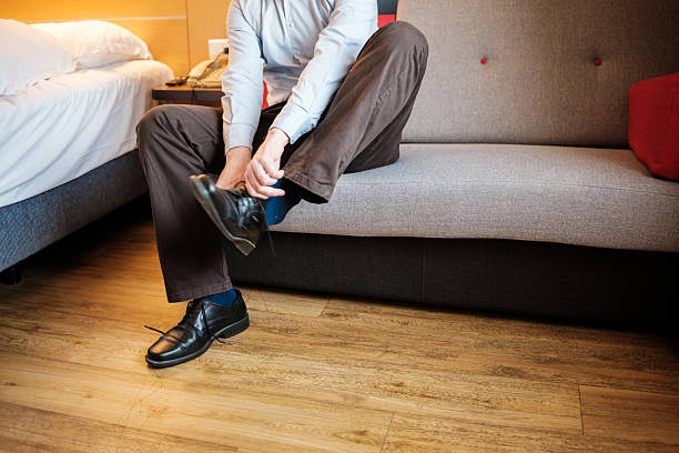 istock Businessman putting on shoes in hotel room getting ready for work 2221211094
