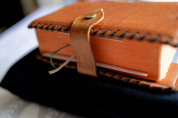 Leather-bound book with a handcrafted cover rests on a dark cloth, evoking a sense of timeless knowledge and tradition