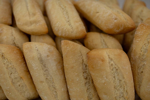 Close-up of a pile of freshly baked crusty bread rolls, showcasing their golden-brown color and inviting texture
