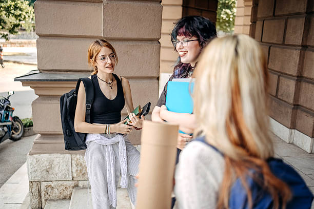 Friends enjoying together after class on university having a coffee while standing on stairs