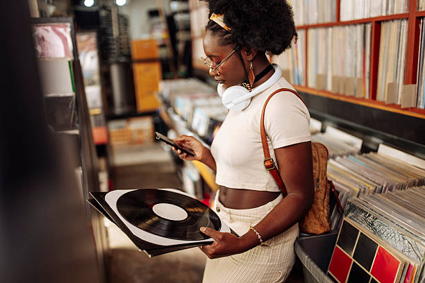 istock Black Woman Browsing Vinyl Records With Cellphone In Hands 2221211668