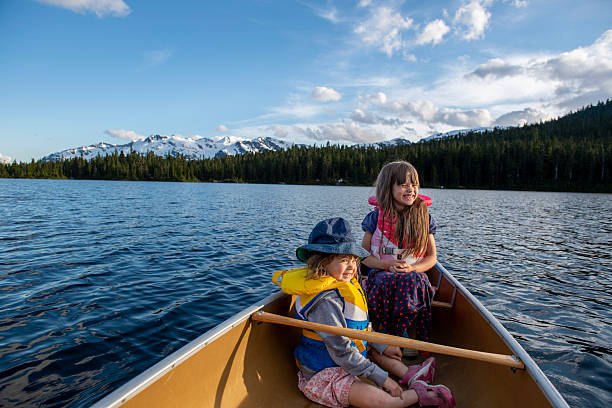istock Young girls in canoe on tranquil lake 2221212751