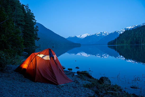Tent near mountain lake at camping in twilight