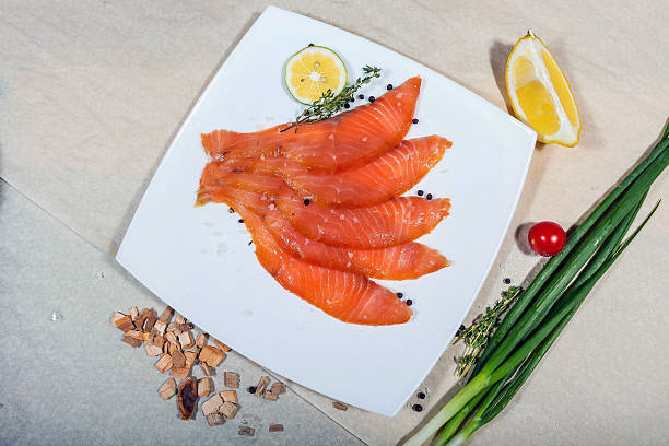 istock Red fish sliced in slices lies on a white plate. Around vegetables and slivers 2221215443