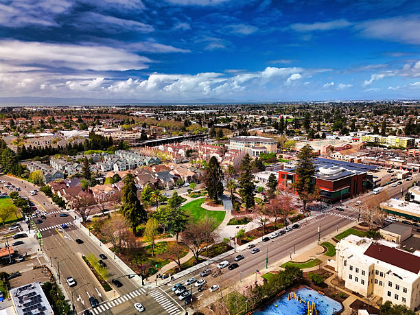 Aerial of Hayward with residential areas, a park, Hayward Ctiy Hall (right of center) and Hayward Public Library (right) in view.  Hayward is part of the San Francisco Bay Area.